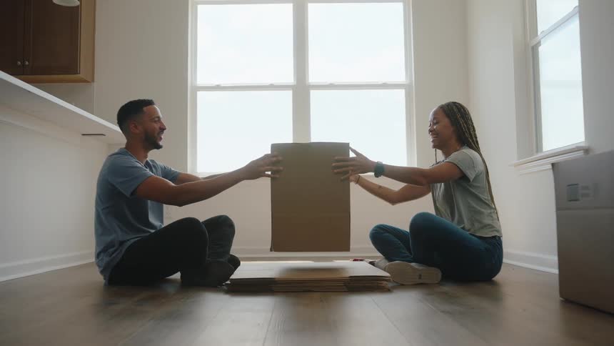 A man hands a woman an assembled cardboard box and high fives her