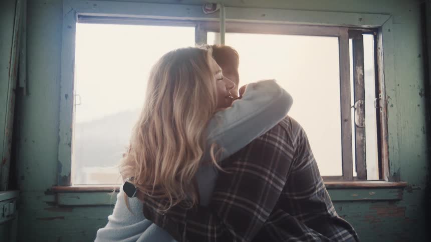 The couple hug by the window