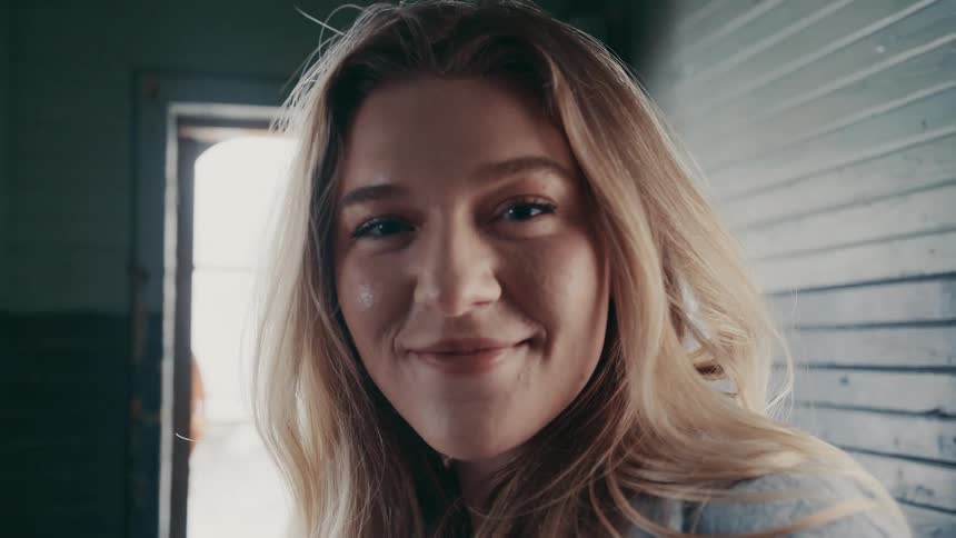 The video is a very short closeup shot of a young woman with long blonde hairshe looks directly at the camera and offers a warm subtle smile