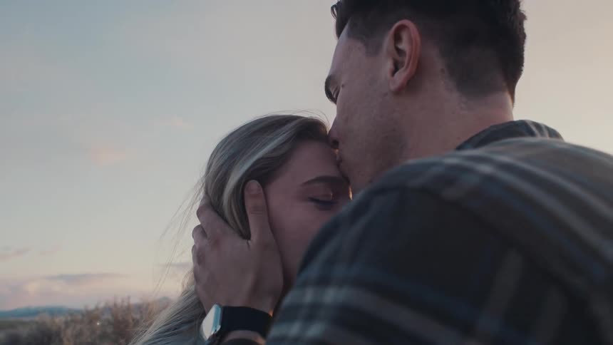 A man kisses a woman on her forehead