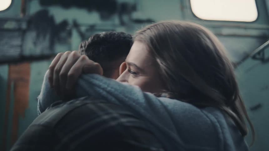 A young couple embrace in a worn down rustic building