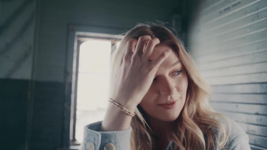 The woman sits and brushes her hair back