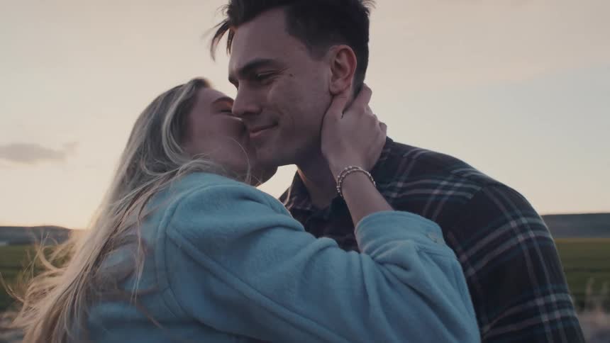 The woman leans in and kisses the man on the cheek
