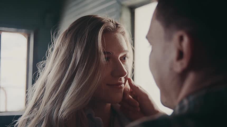 Close up of a young couple kissing each other while standing in a room during daytime