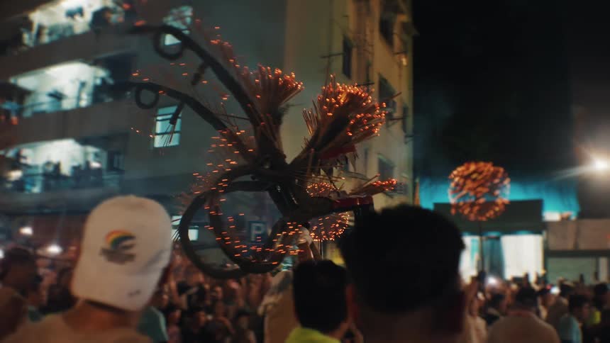 A group of men celebrating with decorations at an outdoor festival in a metropolitan city at night