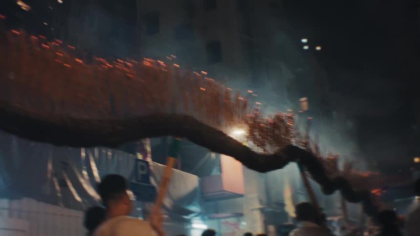 Men lift a dragon structure covered with burning incense sticks during the parade