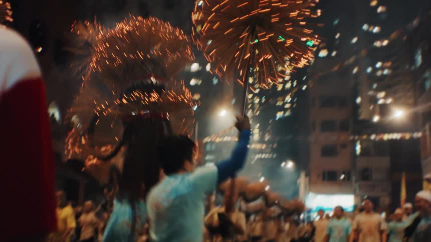 A group of people celebrating with decorations at a festival outdoors in a metropolitan city at night