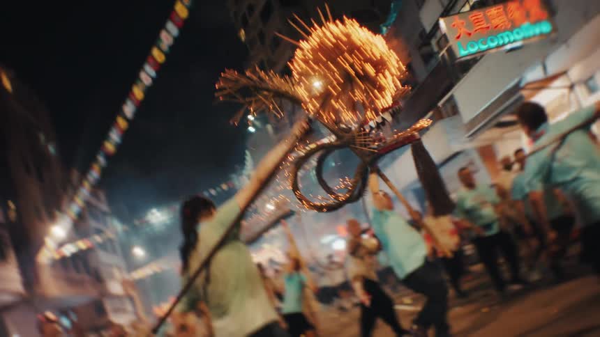 A group of people celebrating with colourful decorations at an outdoor festival in a metropolitan city at night