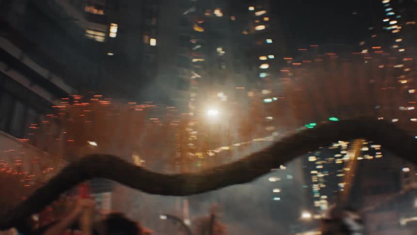 Fire serpent moves along the street during a nighttime celebration surrounded by illuminated buildings