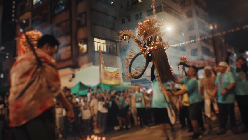 Fire dragon moves forward among dancers and spectators in the lit streets