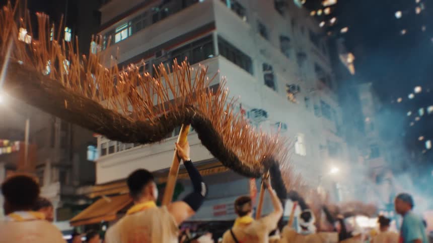Group carries a fire dragon through brightly lit streets during a traditional festival
