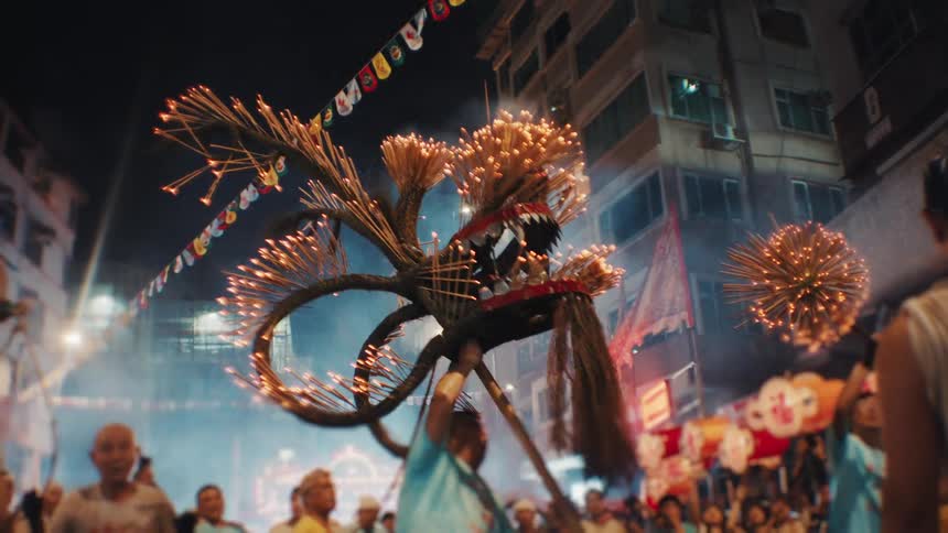 A group of people celebrating with colourful decorations at an outdoor festival in a metropolitan city at night