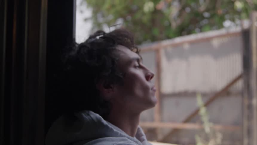 Young man leans his head back and closes his eyes in a moment of rest and reflection