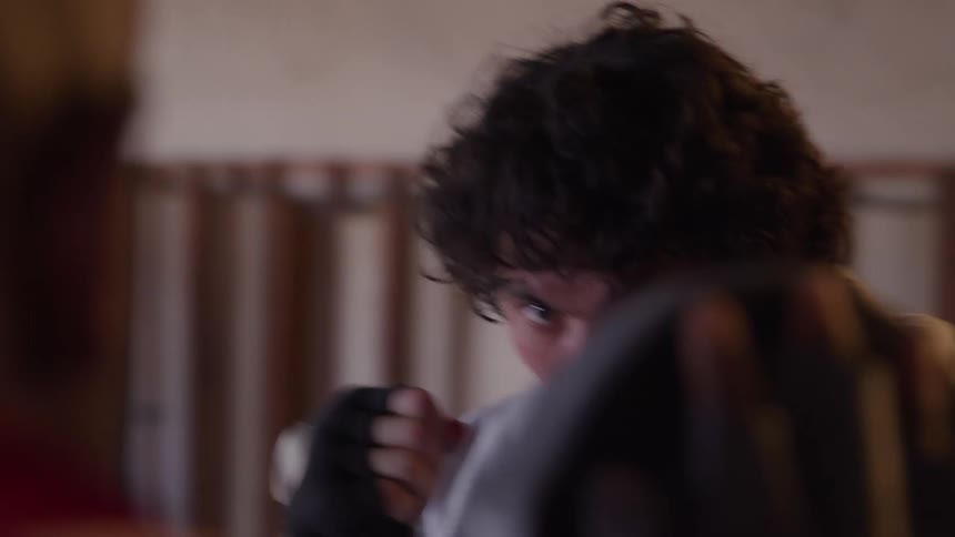 Close up of a young man sparring with a trainer in an indoor boxing ring during daytime