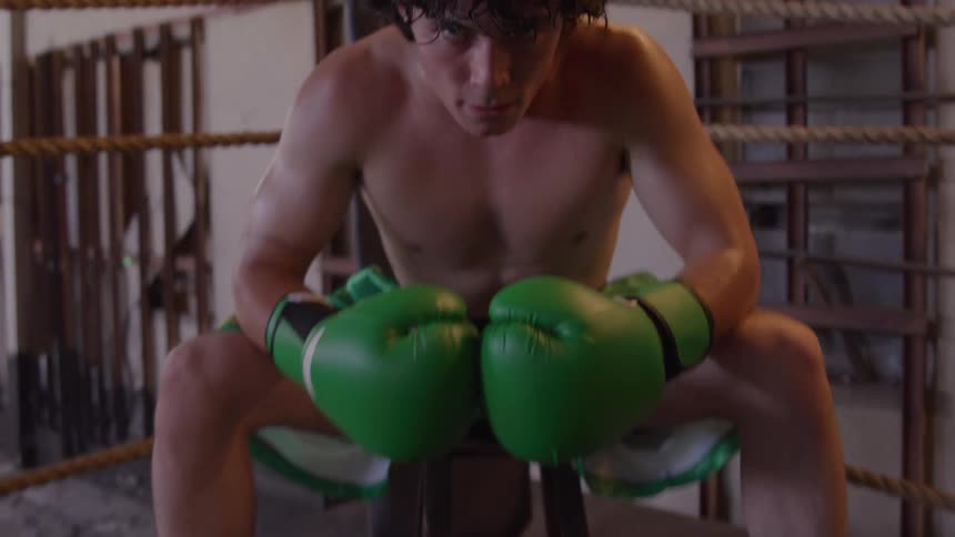 A young male boxer sitting in a ring in preparation for a fight