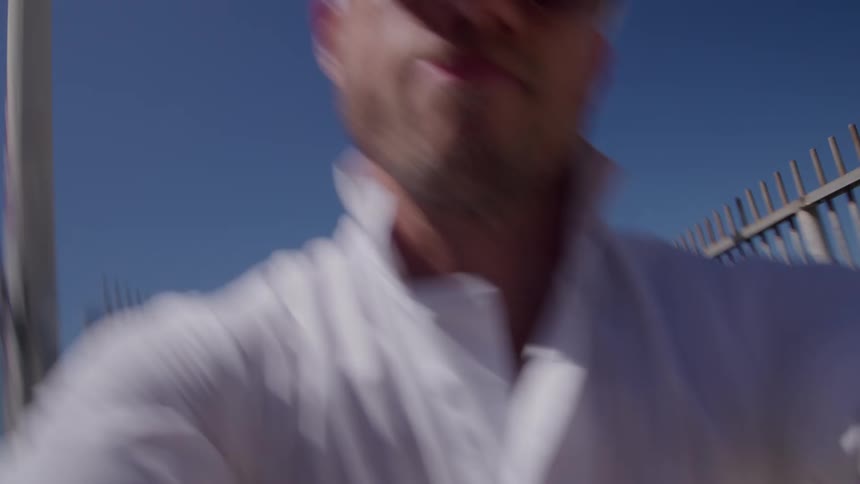 Man dressed in white dances on a walkway under the bright blue sky