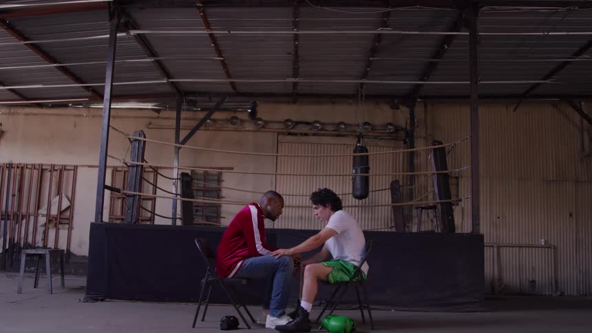 Coach talks to the boxer seated in front of the ring offering encouragement