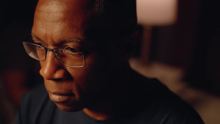 Closeup of a man deep in thought in a dimly lit bedroom