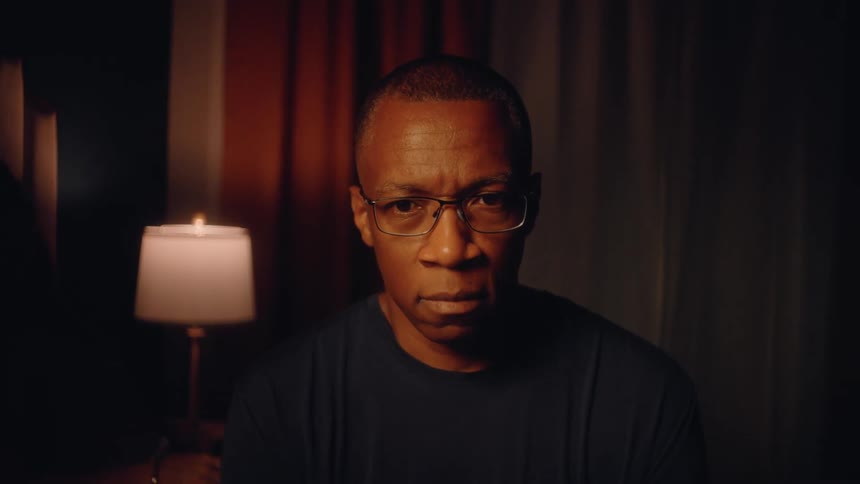 Wife comforts her upset husband in a dimly lit bedroom