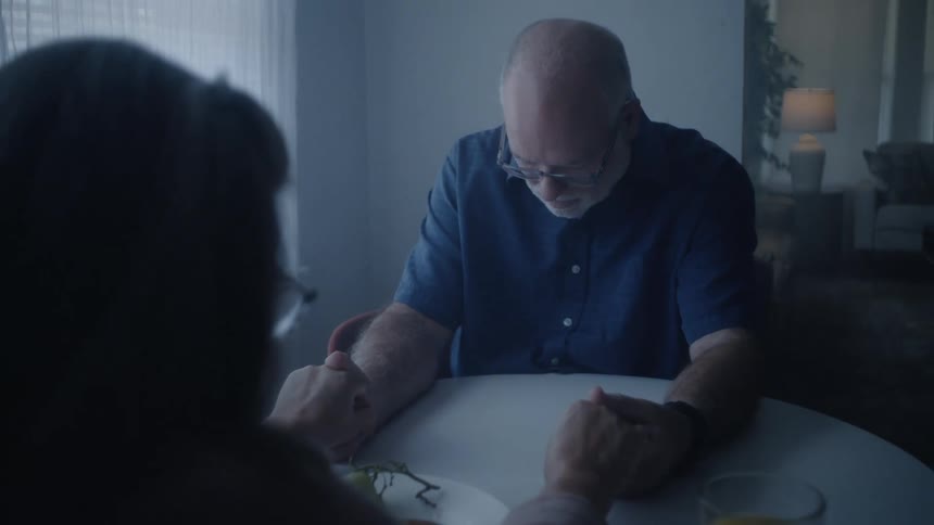 Elderly man gives medication to a woman then prays with her before patting her hand