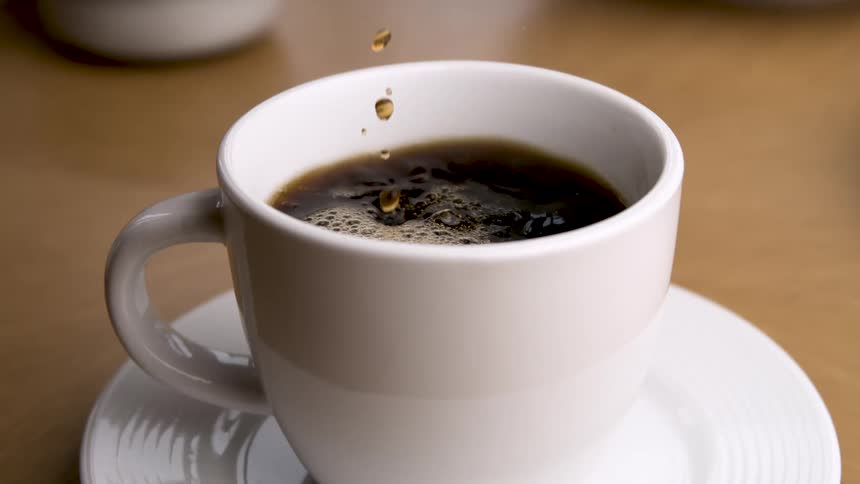 Coffee being poured into a white cup on a saucer