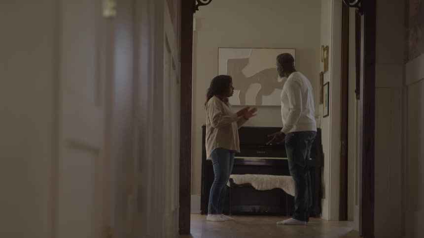 A stressed woman and an aggressive man argue loudly in an apartment hallway