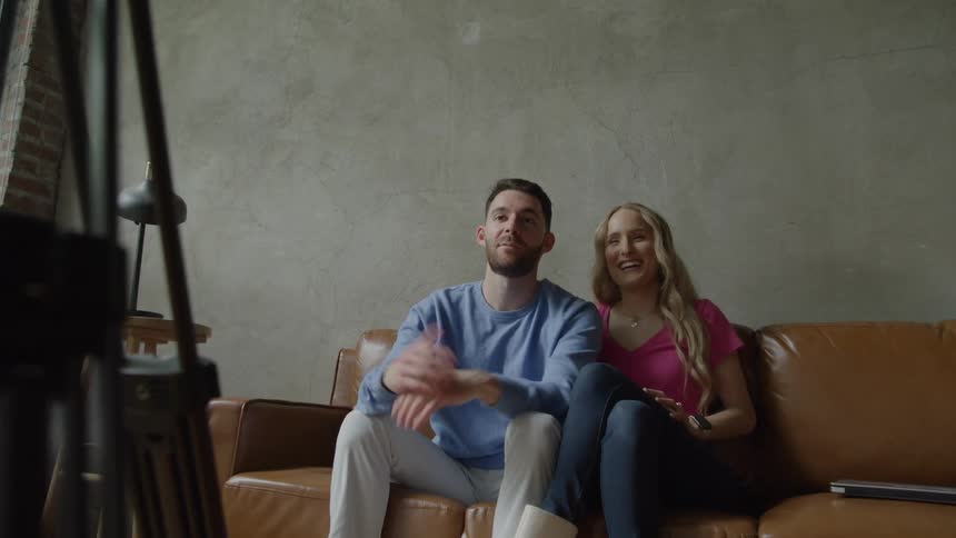 The man and woman talk to the camera in front of them