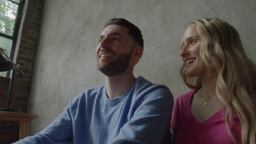 A blogger couple films a video on a sofa in their living room