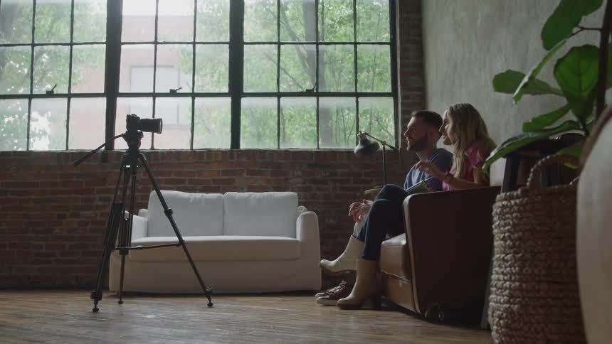 A smiling young blogger couple gets ready to shoot a vlog in a loft
