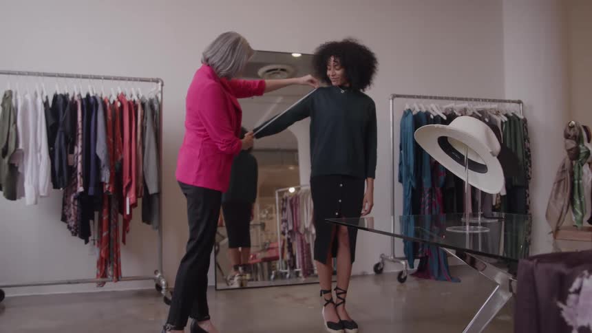 Woman being measured by a seamstress in an elegant clothing studio