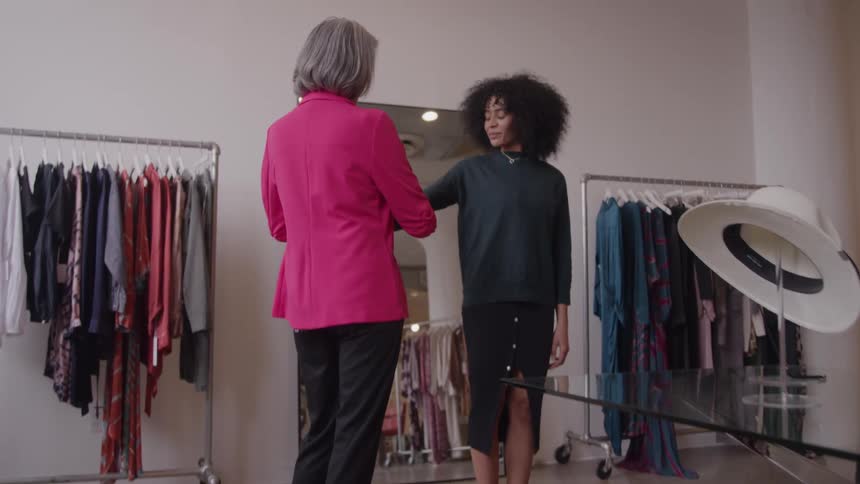 The boutique employee measures a sleeve on a customer