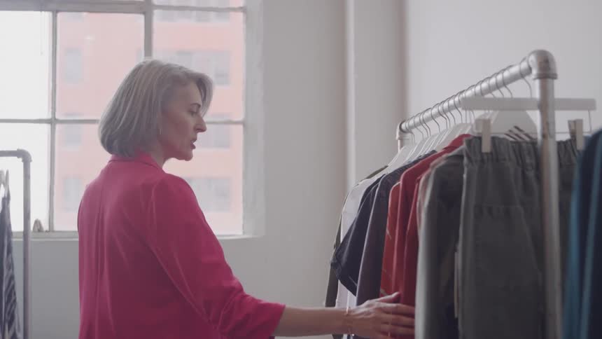 A woman browses a rack of clothes in a well lit modern boutique