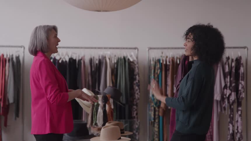 The woman holds up clothing in the store