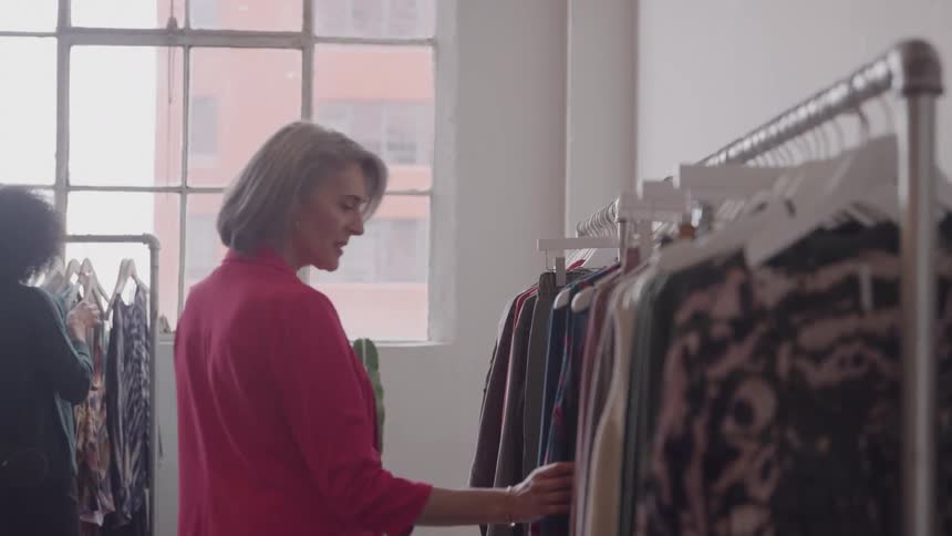 Two women browse through clothing racks in a clothing boutique