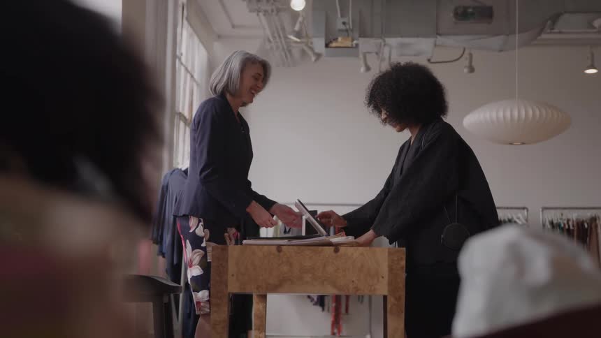 A sales woman cashes out a customer at a clothing store