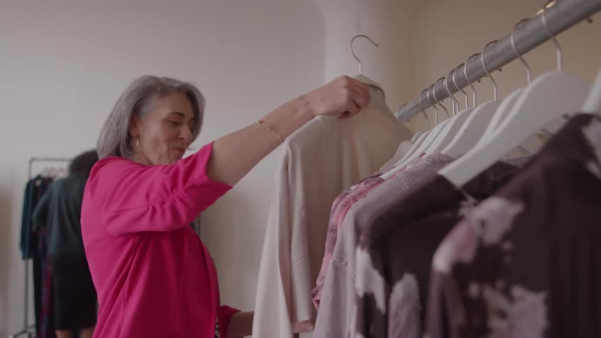 Woman at a store browsing clothes from a clothes rack indoors during day time