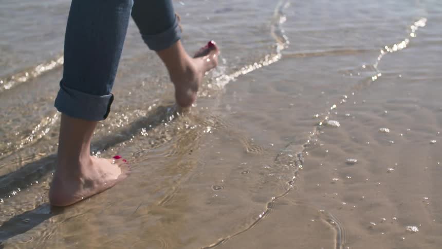 Woman walking in water on a sandy beach