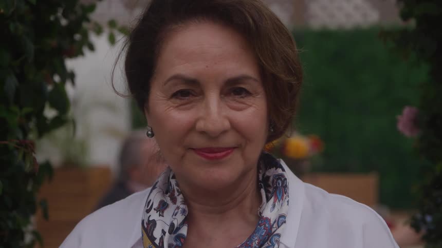 An elegant older woman with a gentle smile looking directly into the camera