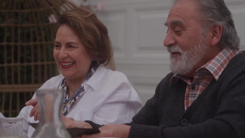 Older man and woman hold cards and smile during the game