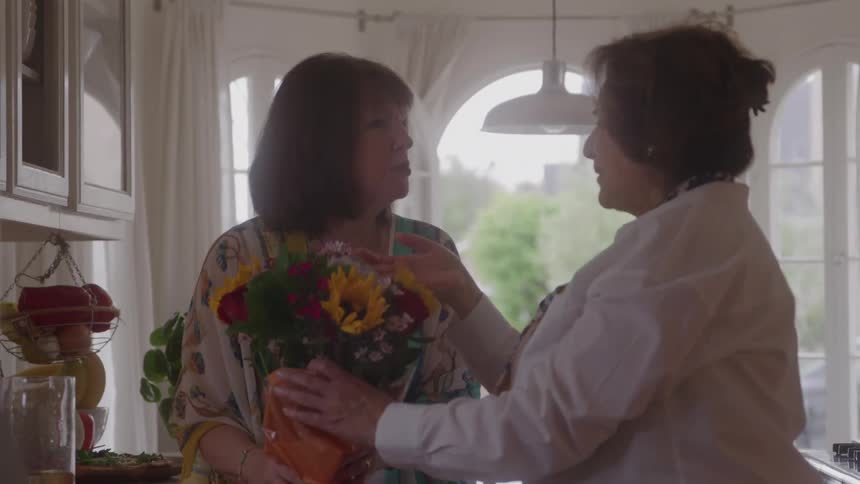 Older women exchange a bouquet of flowers in a gesture of affection