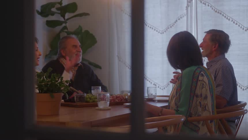 Four older people sitting at a table take turns serving themselves during the meal