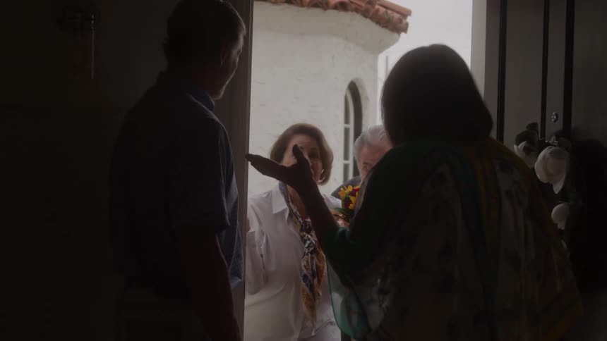 Woman greets guests warmly at her doorstep