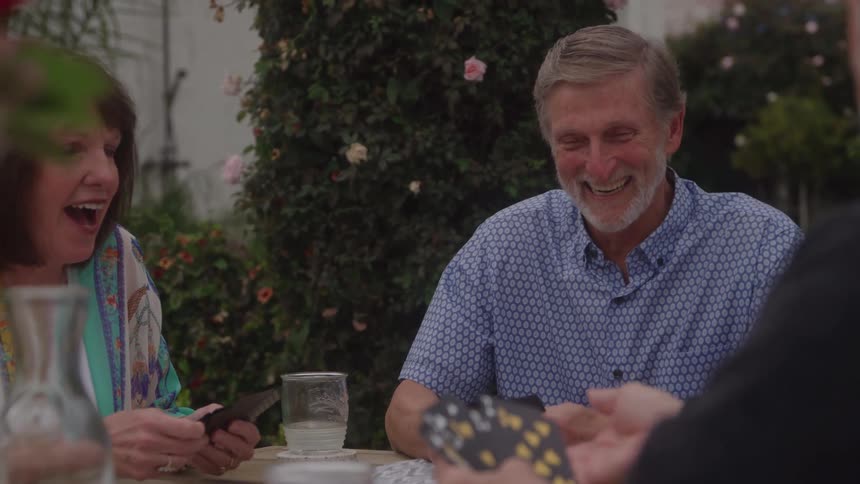 Man in a blue shirt holds cards while participating in a group game