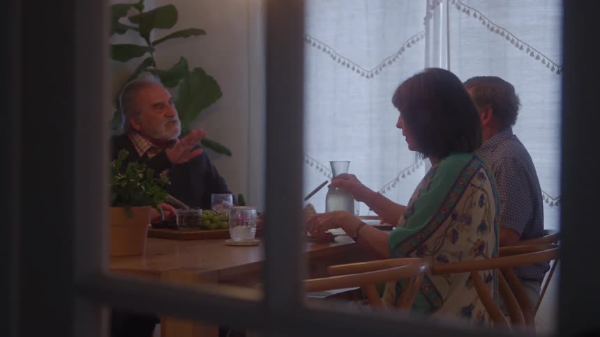 Group of older people sitting at the table talking during a meal