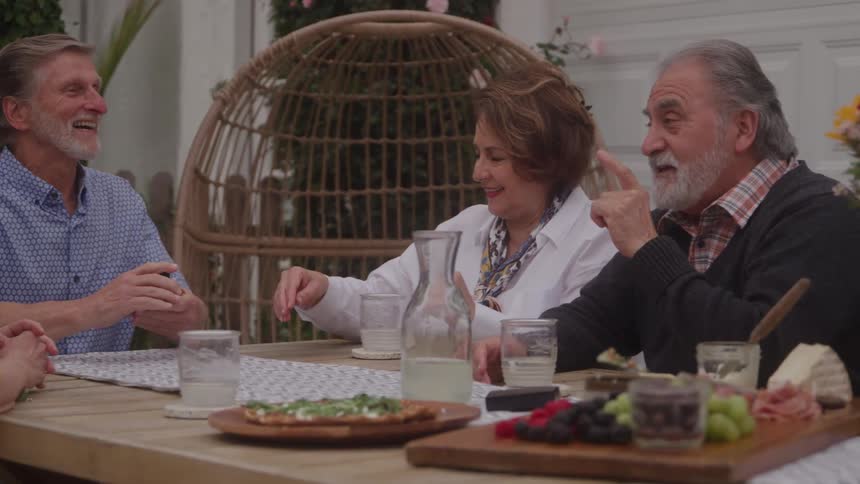 Older couples enjoy talking while sharing a meal outdoors during the daytime