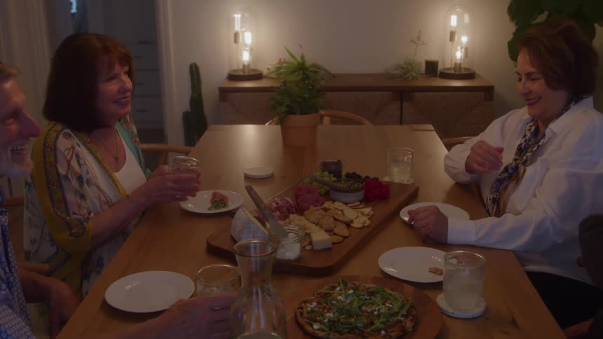 Group of older people sitting at the table having dinner and laughing