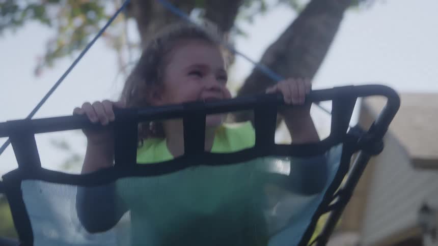Mother pushing her little daughter on the swing