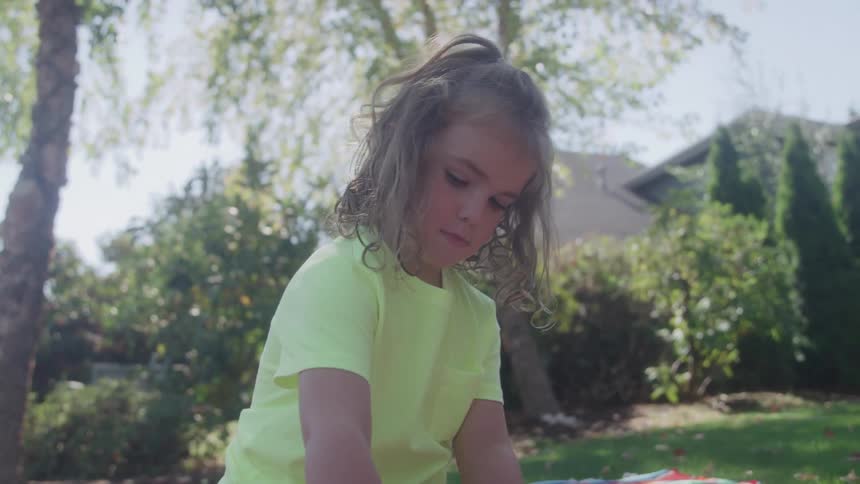 Child sitting on a colorful blanket plays with alphabet pieces