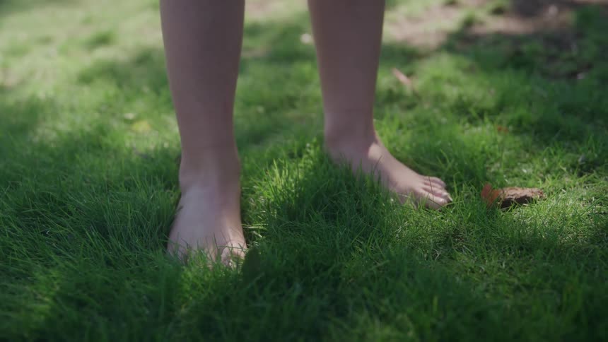 Bare feet resting on green grass under natural light in outdoor setting