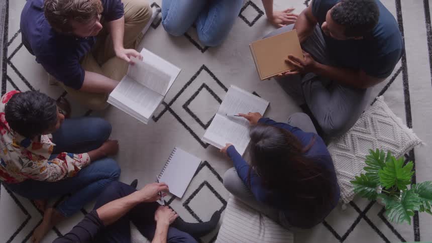 Group of people sitting in a circle reading and sharing notes